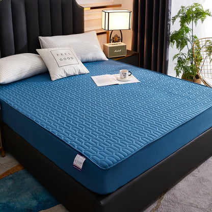 Blue mattress cover on a bed with pillows and a lamp in a bedroom setting
