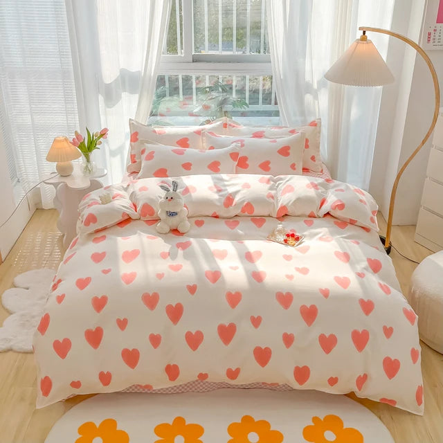 Heart-patterned bedding set in a bright bedroom with white curtains and a lamp.
