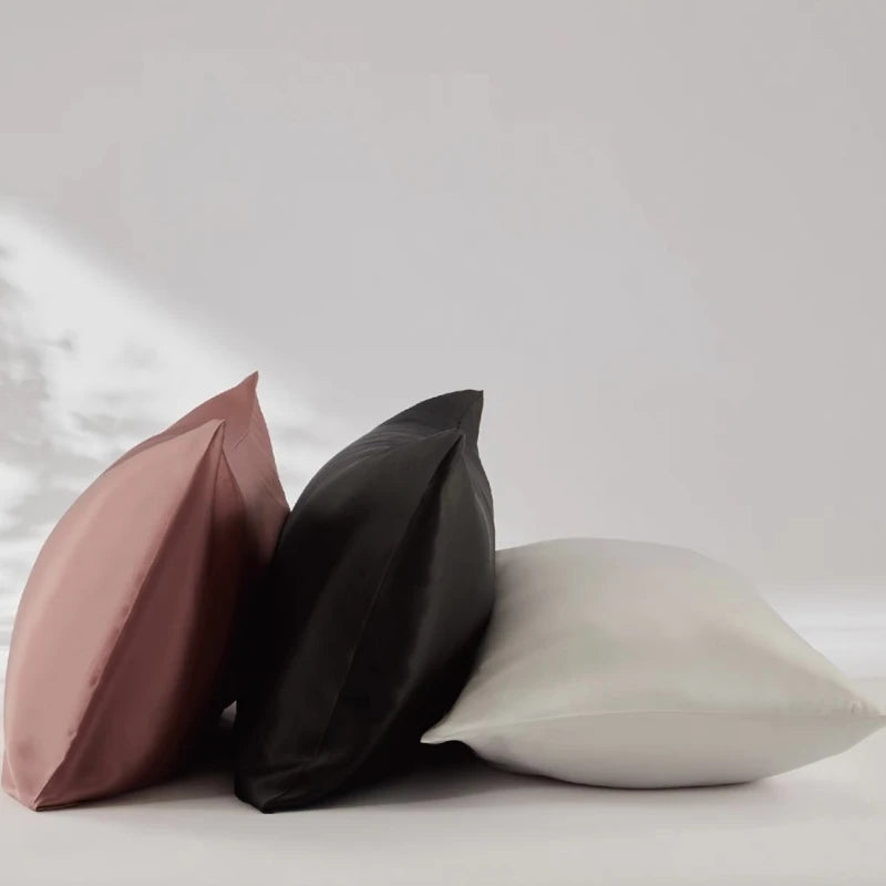 Three pillows in pink, black, and white on a light gray background