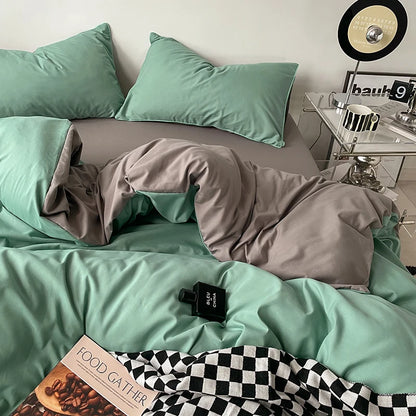 Mint green bedding set with gray comforter on a bed, next to a nightstand with a clock.