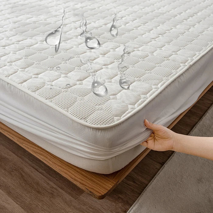 Mattress protector being held up to a mattress with water droplets shown above it.