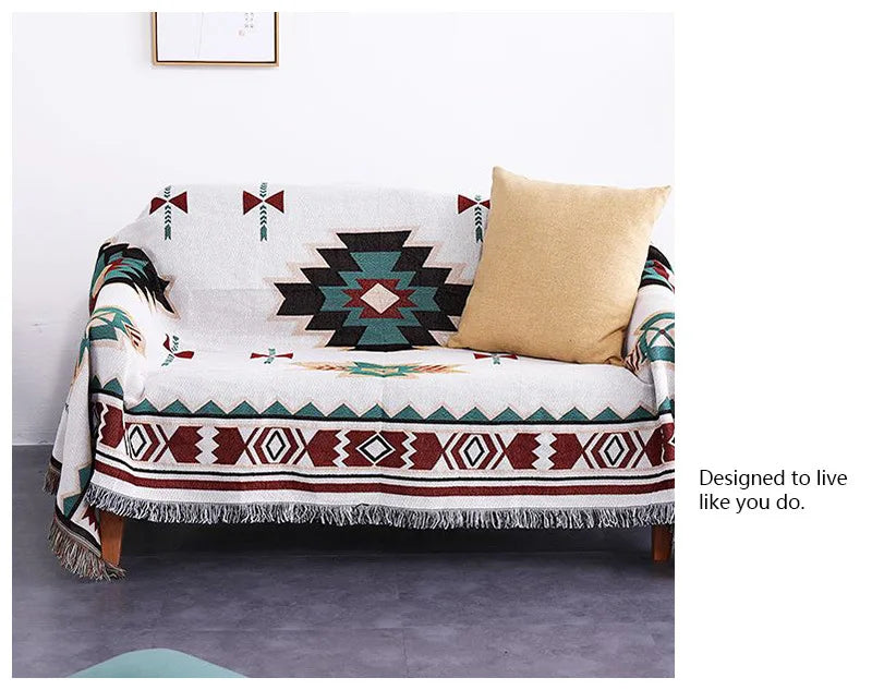 Sofa with a patterned throw blanket and a pillow on a gray floor.
