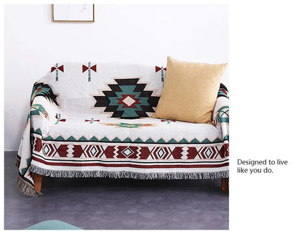 Sofa with a patterned throw blanket and a pillow on a gray floor.
