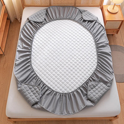 Gray quilted mattress cover on a bed in a bedroom setting