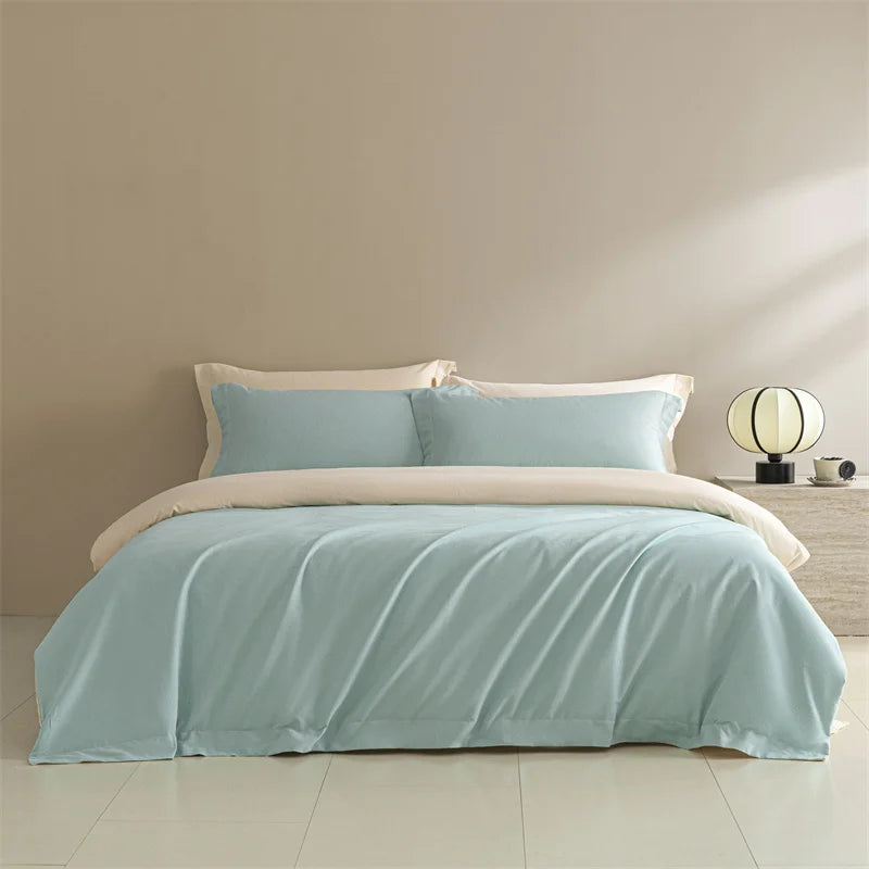 Light blue bedding set with beige comforter on a bed in a room with a lamp and nightstand.