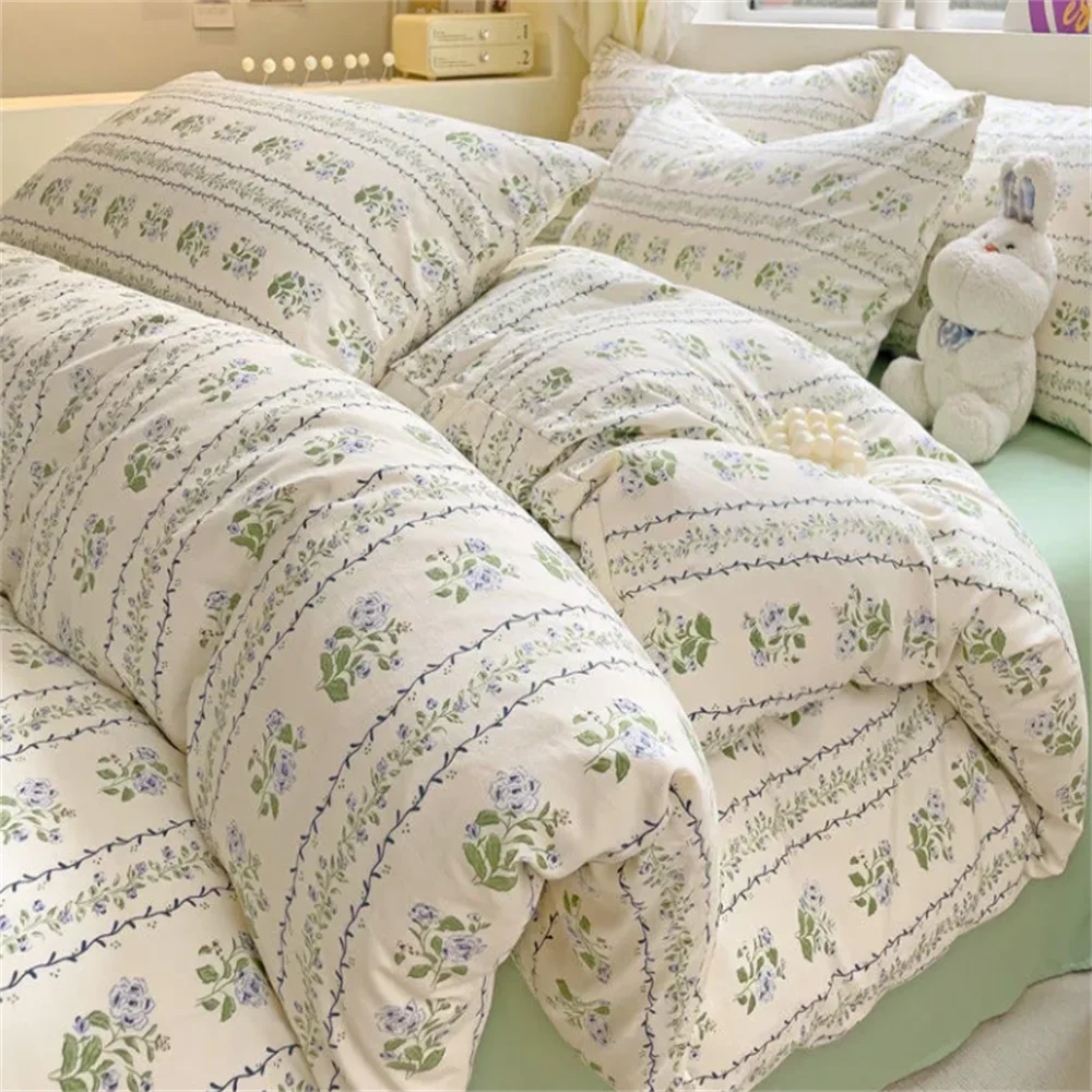 Floral patterned bedding set on a bed with pillows and a teddy bear.