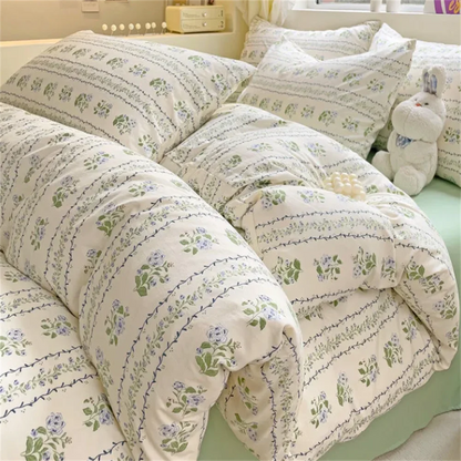 Floral patterned bedding set on a bed with pillows and a teddy bear.