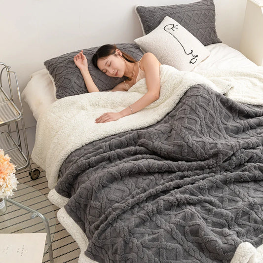 Woman sleeping on a bed with a textured gray and white blanket