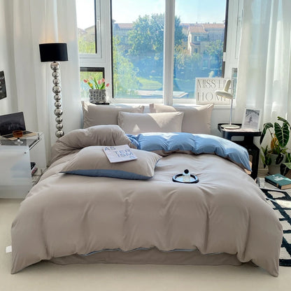 Neatly made bed with beige bedding and blue pillows in a bright bedroom.