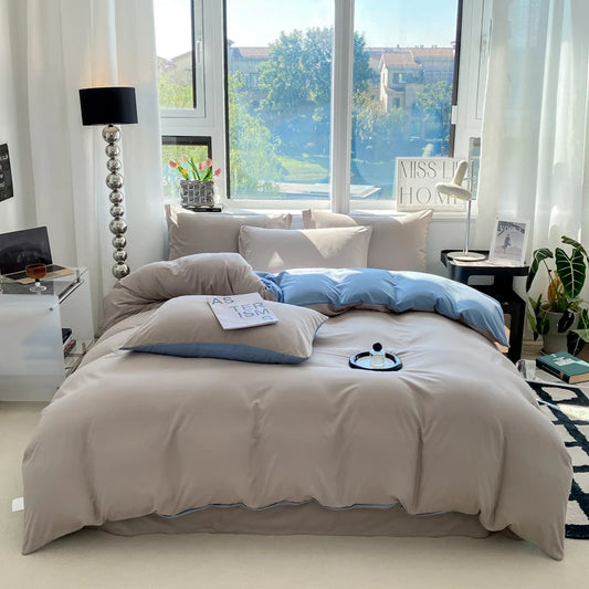 Neatly made bed with beige bedding and blue pillows in a bright bedroom.
