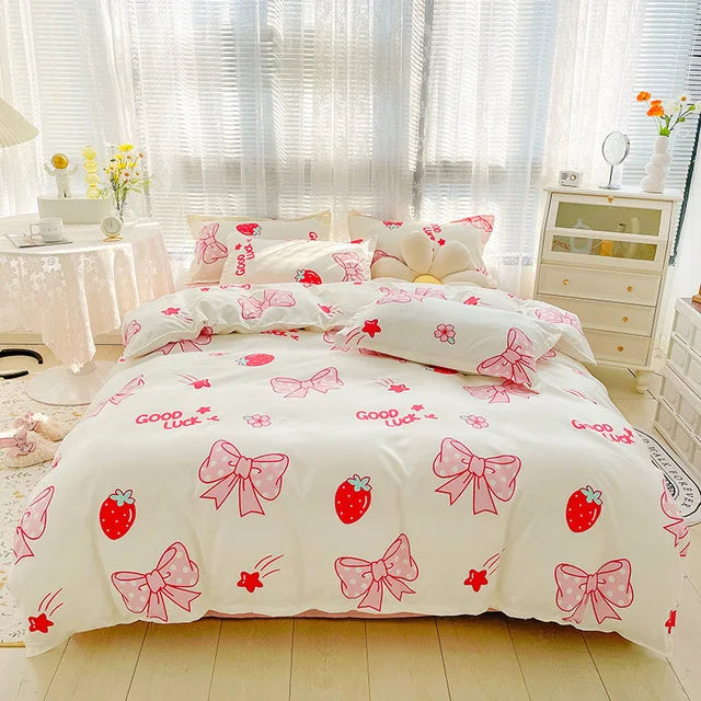 Bedding set with red bows and strawberries on a white comforter in a bedroom.