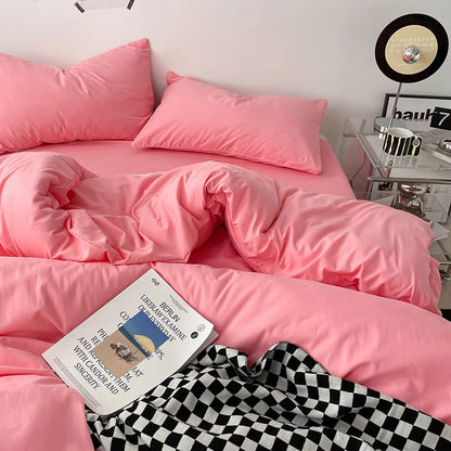 Pink bedspread on a bed with a book and checkered blanket in a bedroom setting.