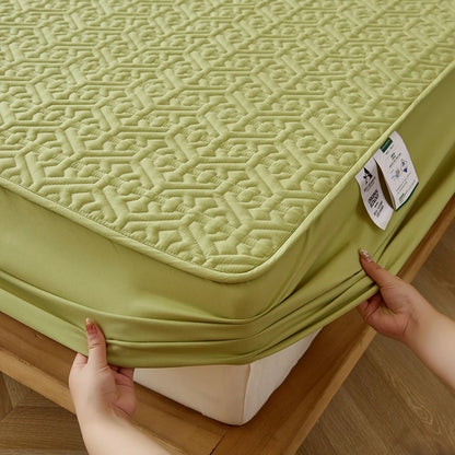 Green mattress cover with a geometric pattern being adjusted on a bed.