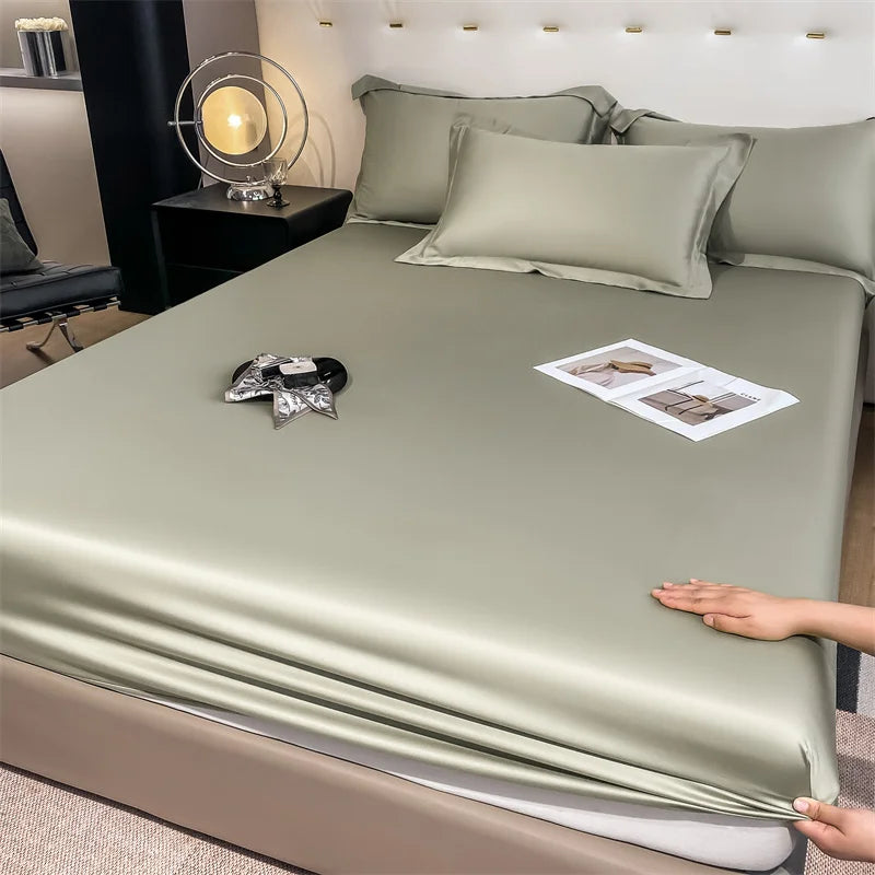 Person spreading a green satin sheet on a bed with a magazine and decorative items.