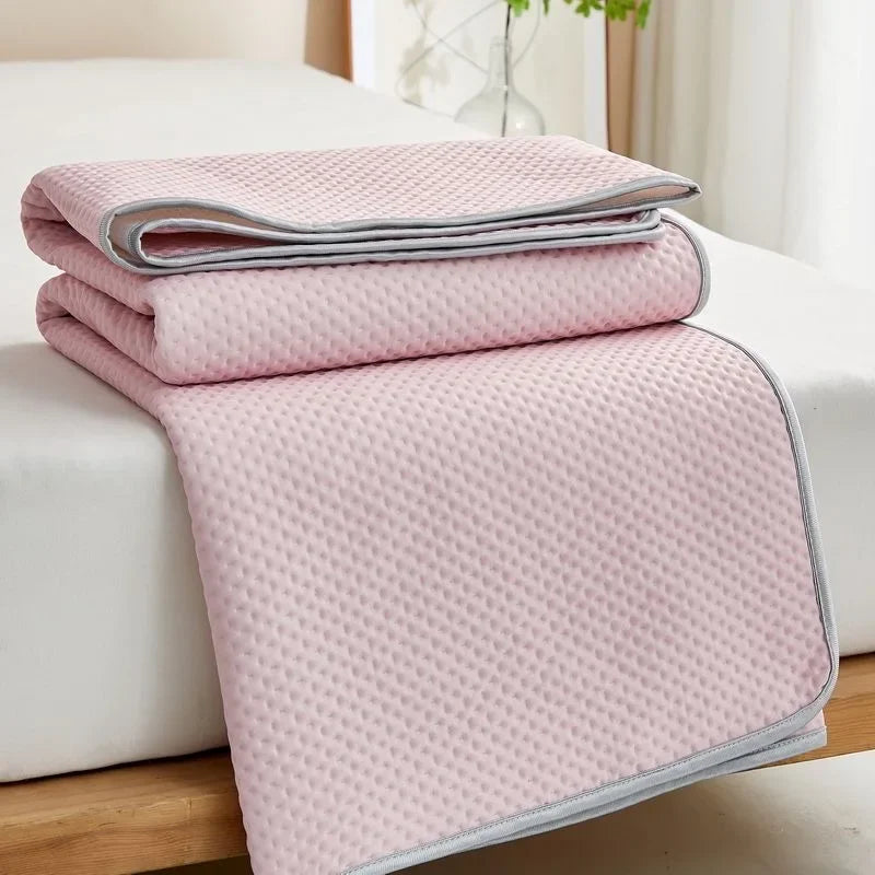 Pink quilted blanket on a bed with a light background