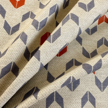 Close-up of fabric with geometric pattern in red, blue, and beige.