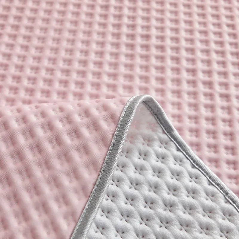 Close-up of a textured pink fabric with a corner folded over to reveal a white quilted surface.