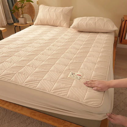 Beige quilted mattress cover on a bed with a person adjusting it, in a bedroom setting.