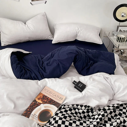 Bed with white bedding, navy blanket, and a book titled 'Food Gather' on a nightstand.