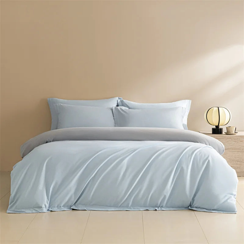 Light blue bedding set on a bed with a beige wall and lamp in the background