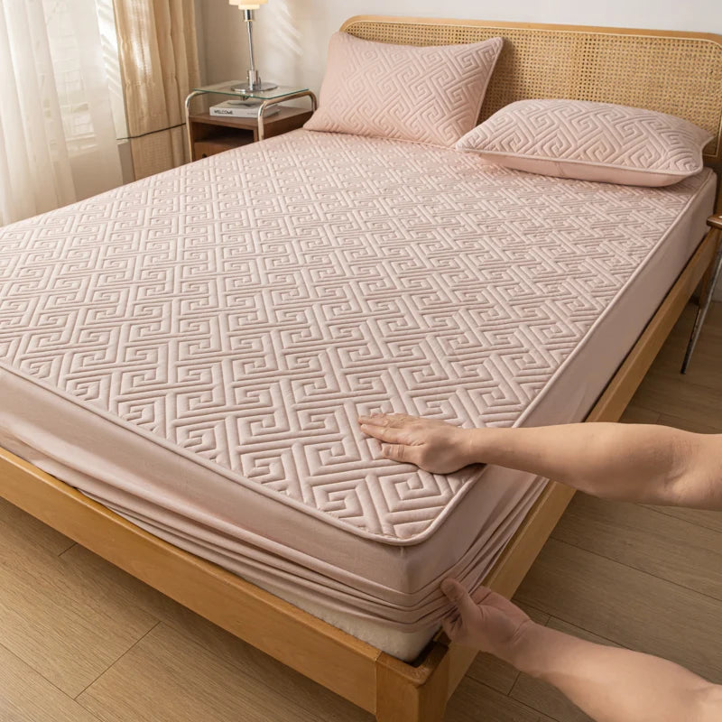 Person adjusting a geometric-patterned mattress cover on a bed in a bedroom.