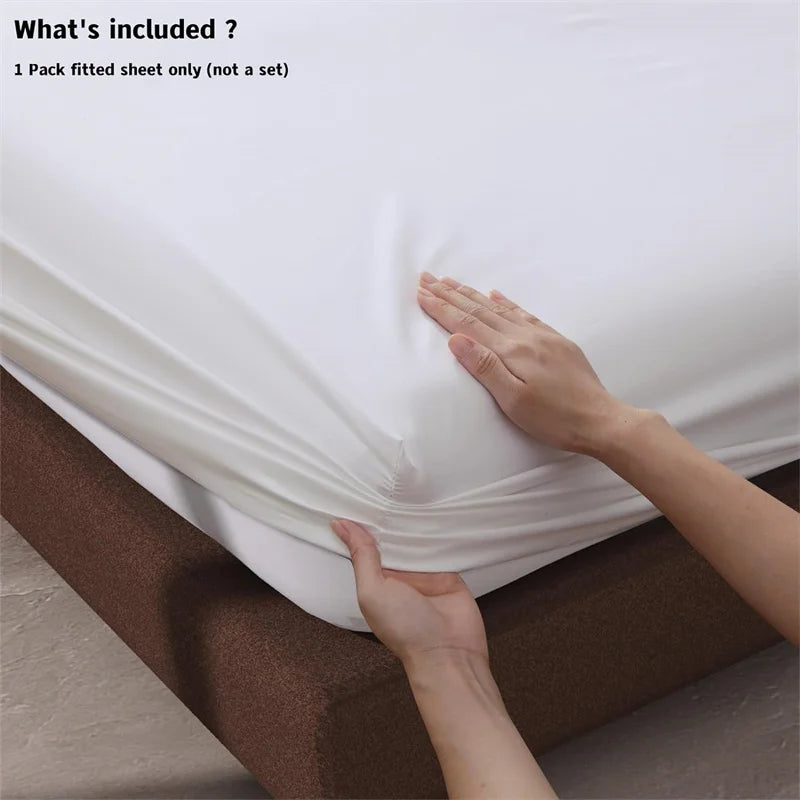 White fitted sheet being stretched over a mattress with hands on a neutral background