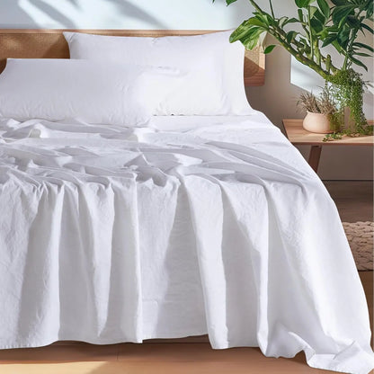White bedspread on a bed with a wooden headboard and plants in the background