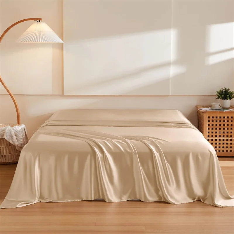 Beige satin sheet on a bed in a bedroom setting with a lamp and plant.