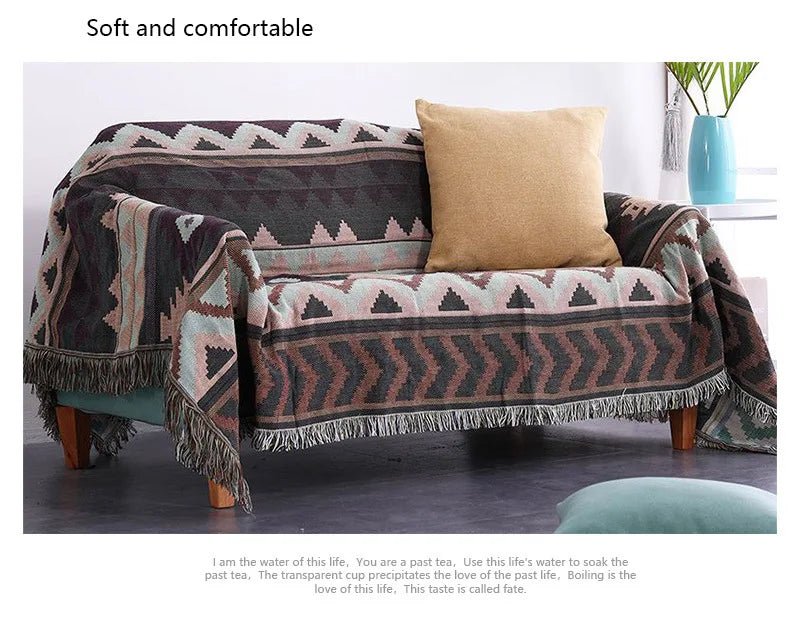 Sofa with patterned throw blanket and pillow on a plain background