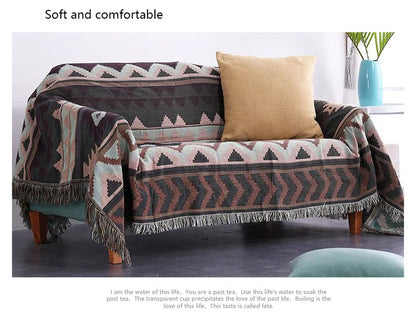 Sofa with patterned throw blanket and pillow on a plain background