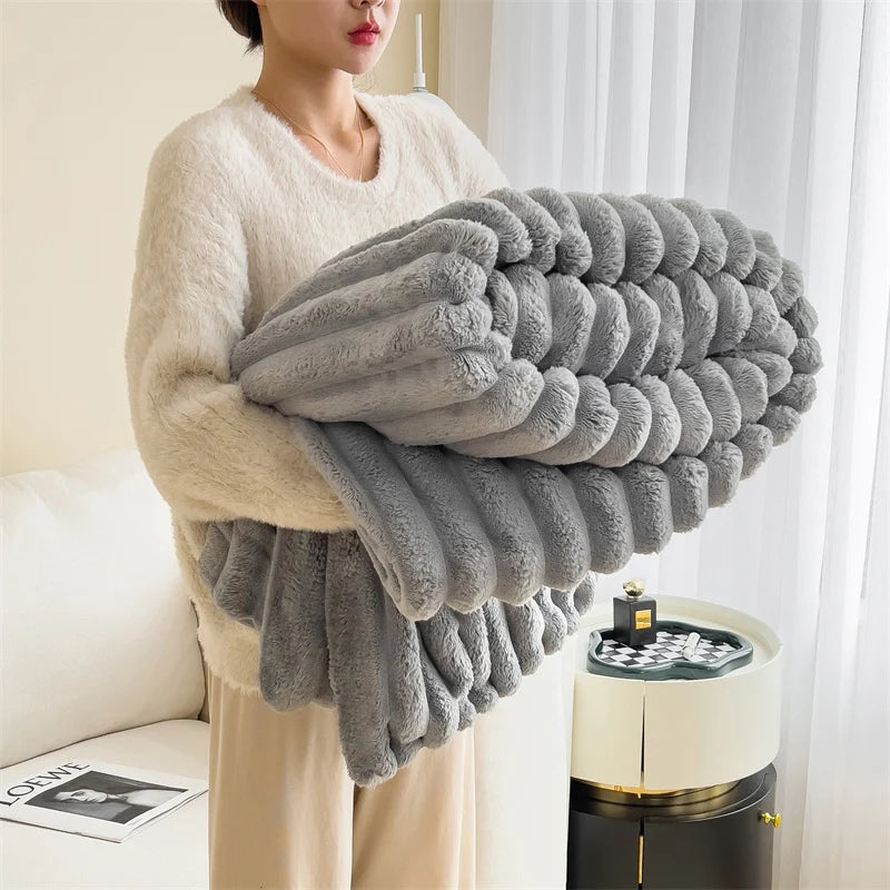Person holding a large gray textured blanket in a living room setting.