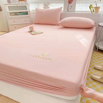 Pink bed sheet with 'Charming' branding on a bed in a bedroom setting.