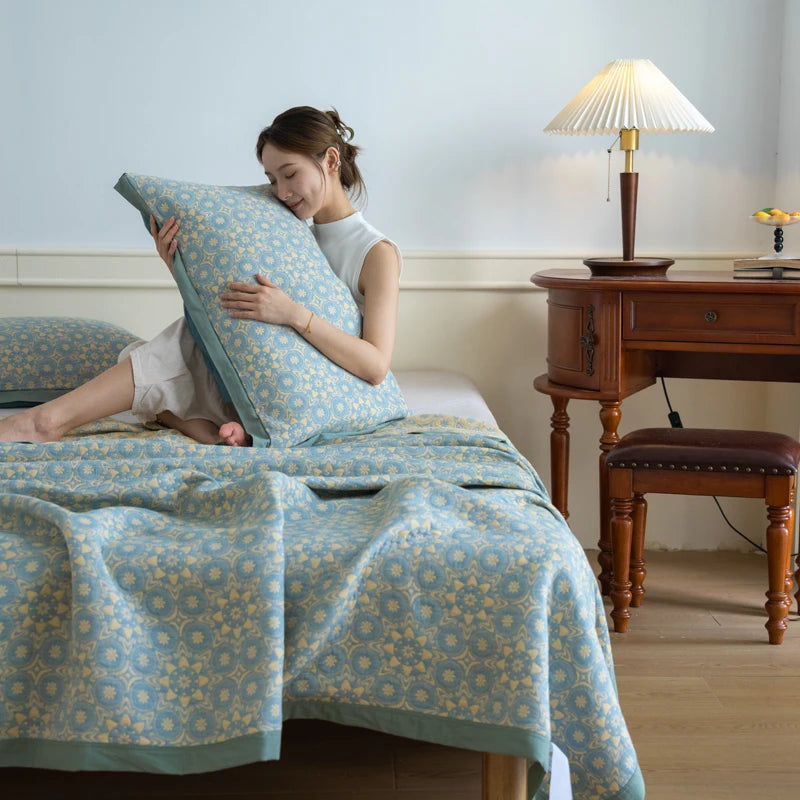 Woman lying on a bed with a floral patterned quilt and pillow, in a room with a wooden nightstand and lamp.