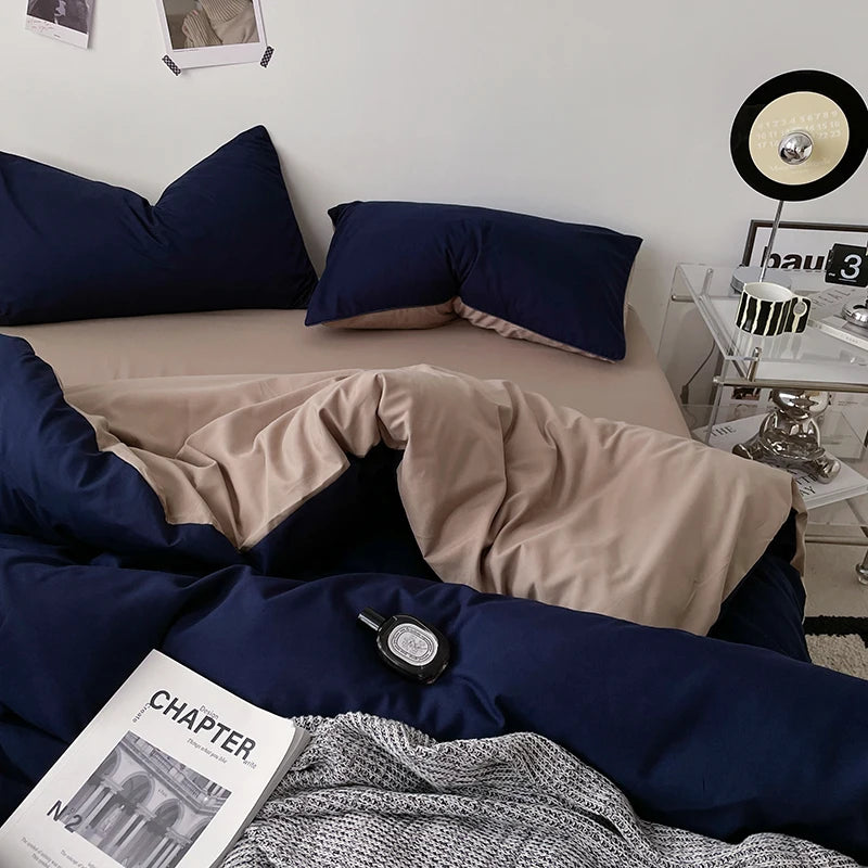 Bedroom with navy bedding and beige comforter, nightstand with decor items.