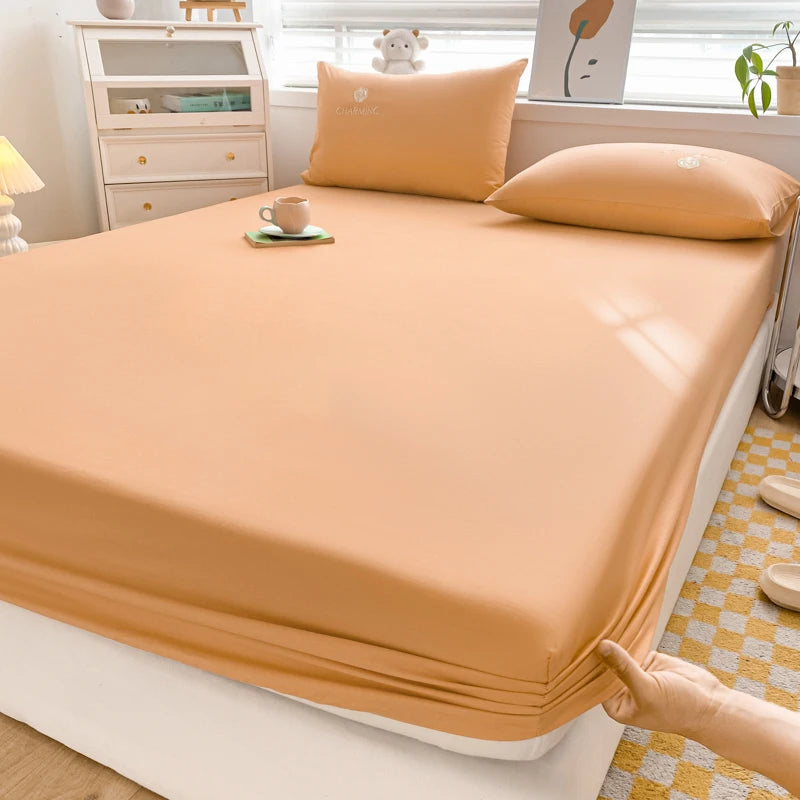 Person holding a fitted sheet on a bed in a bedroom setting