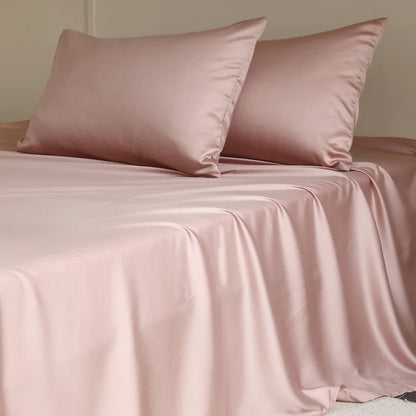 Pink satin sheet set with two pillows on a bed.