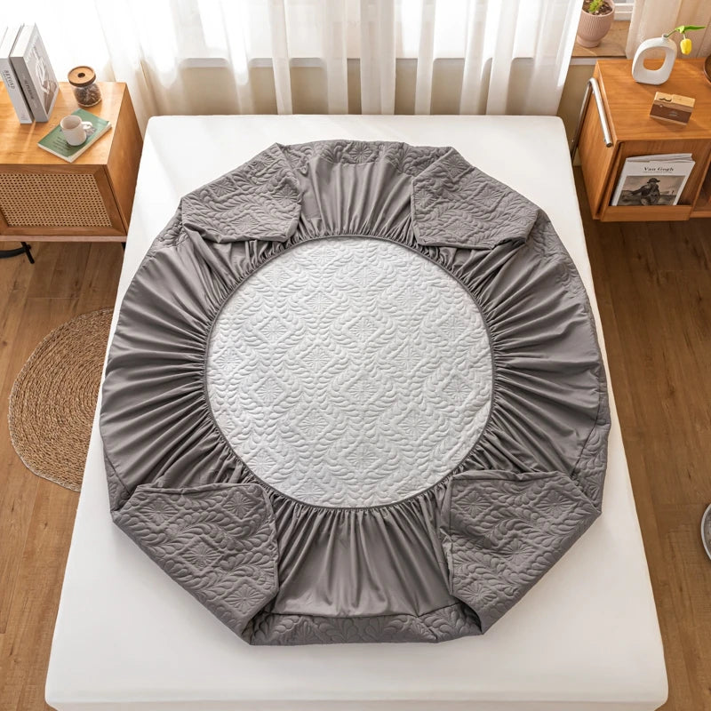 Gray fitted sheet on a round mattress in a bedroom setting