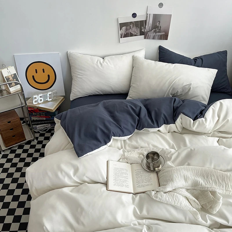 Bed with white and navy bedding, open book, and small cup on a checkered floor.