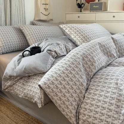 Bed with patterned bedding and a cup on a nightstand in a bedroom setting.
