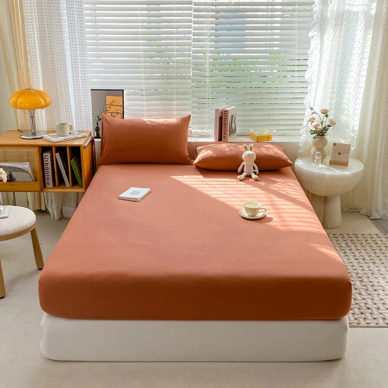 Bed with orange bedding in a bright room with window blinds and decor items.