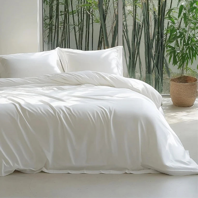 White bedding set on a bed with a bamboo wall and plant in the background