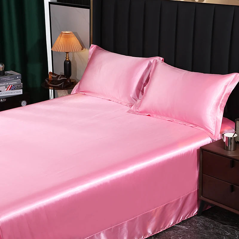 Pink satin bedding set on a bed with a dark headboard and lamp in the background.