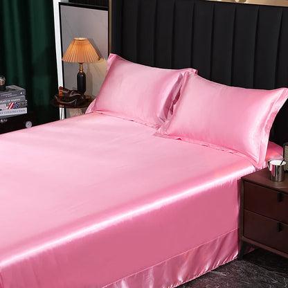 Pink satin bedding set on a bed with a dark headboard and lamp in the background.