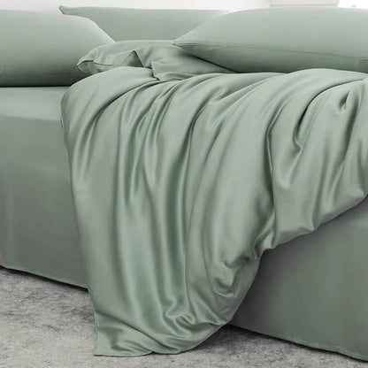 Green bedspread on a bed with pillows in a neutral room.