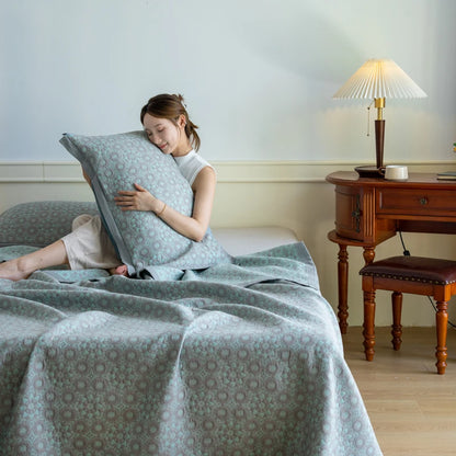 Woman lying on a bed with a patterned comforter and pillow, in a bedroom setting.