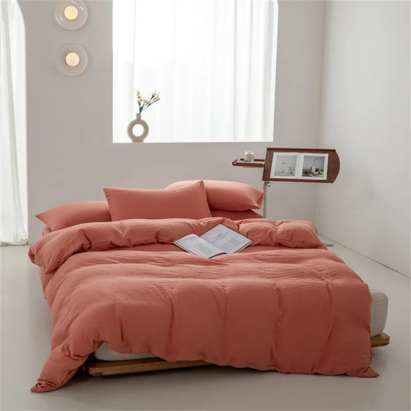 Bed with pink bedding in a minimalistic room with a window and lamp.