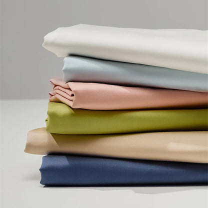 Stack of folded fabric sheets in various colors on a neutral background