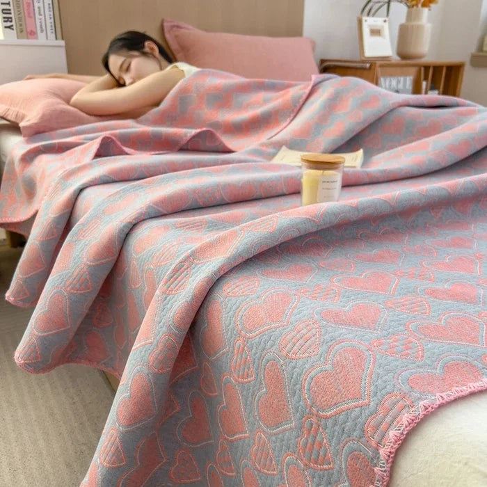 Person lying on a bed with a pink and blue patterned blanket