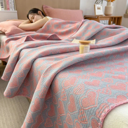 Person lying on a bed with a pink and blue patterned blanket