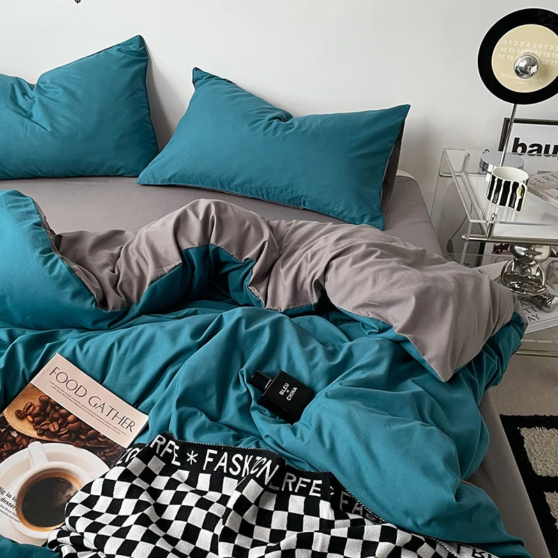 Teal bedding set on a bed with a side table and decor items.